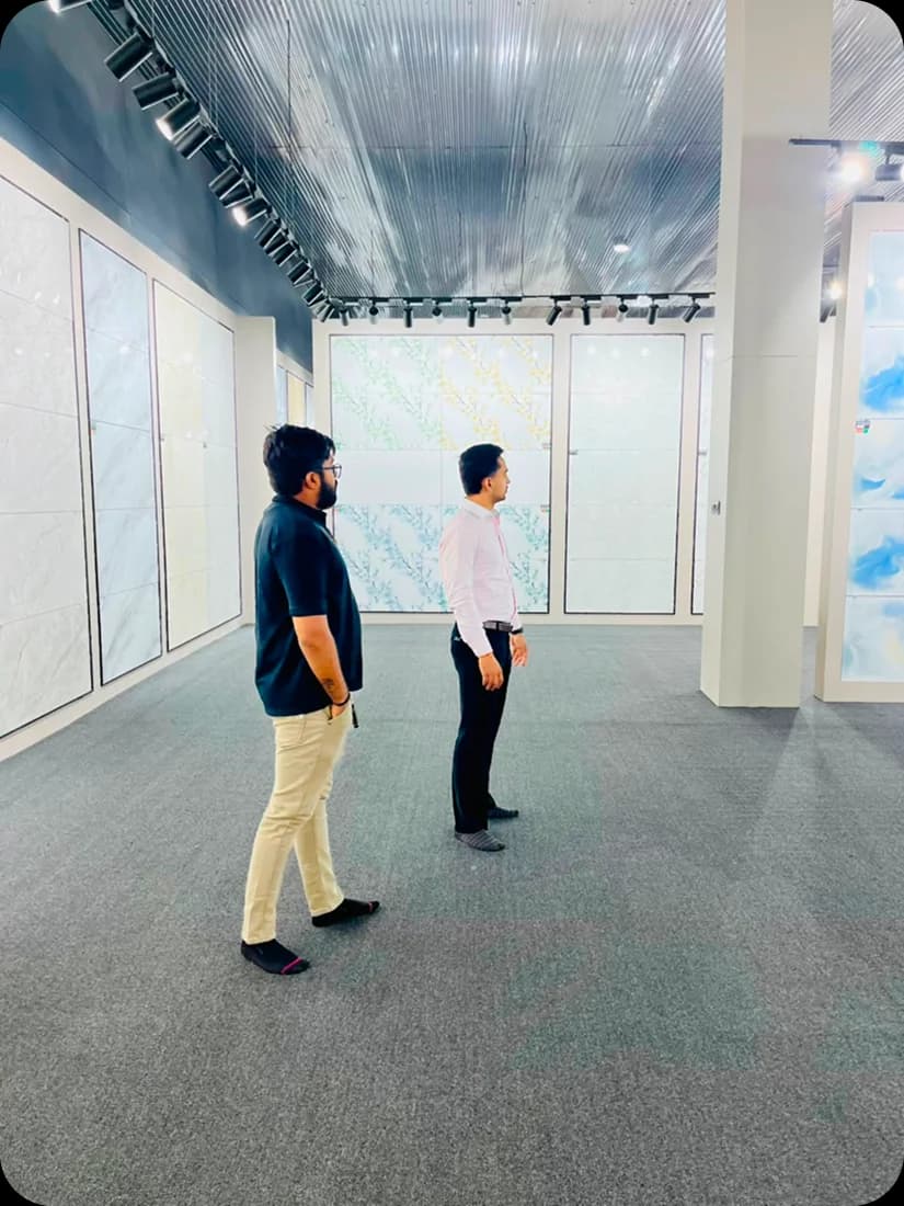 Two JSK Exports staff reviewing a marble-effect wall tile in the showroom